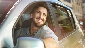 A man smiling while looking outside in his Renault vehicle