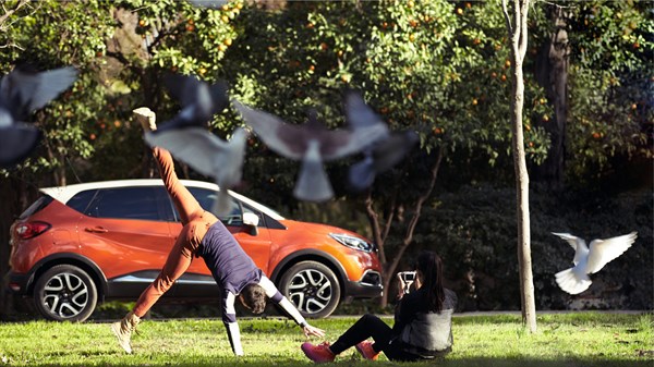 A man doing a cartwheel in front of a Renault CAPTUR